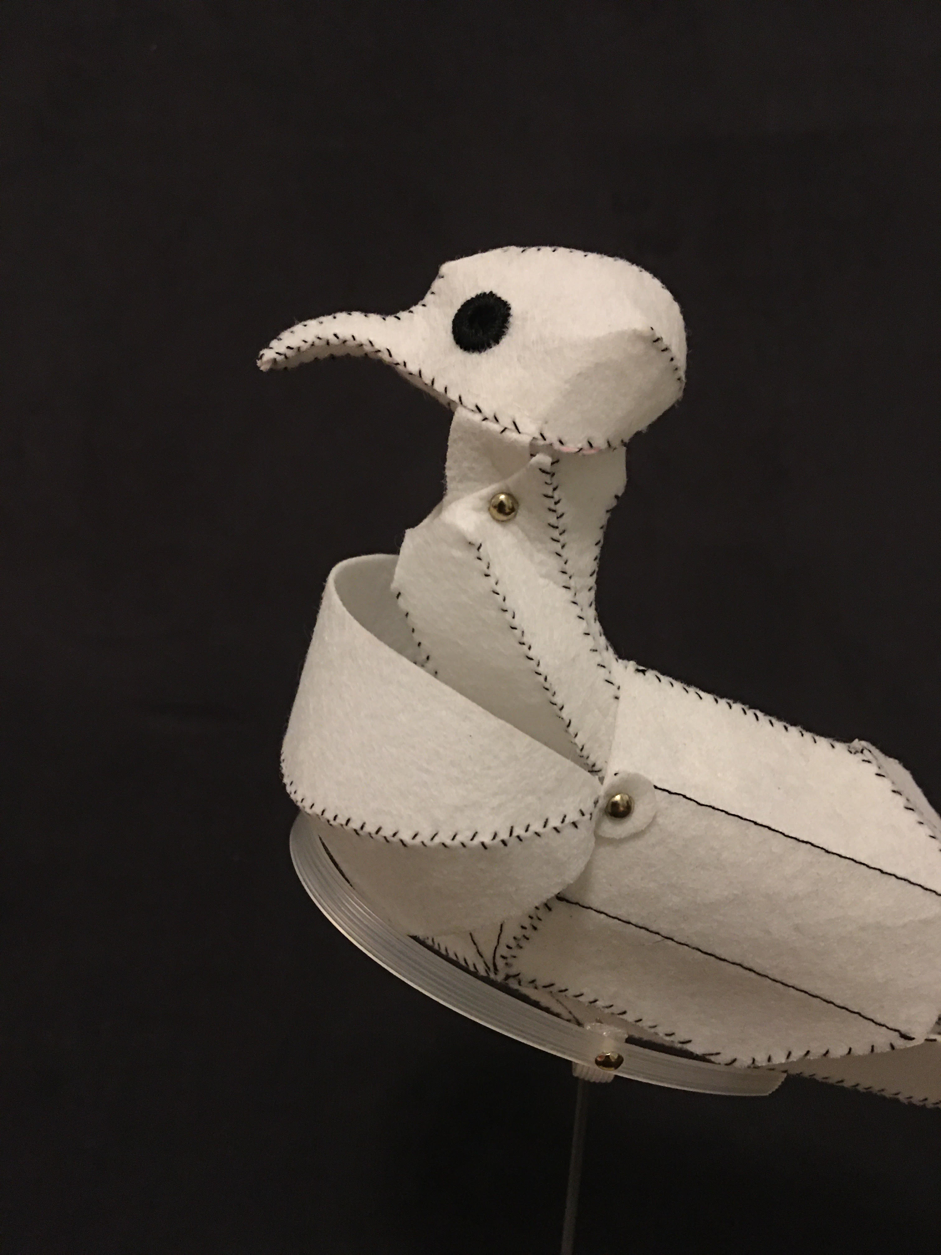 a model pigeon sewed from white interfacing with black contrast thread, detail view centering head and neck